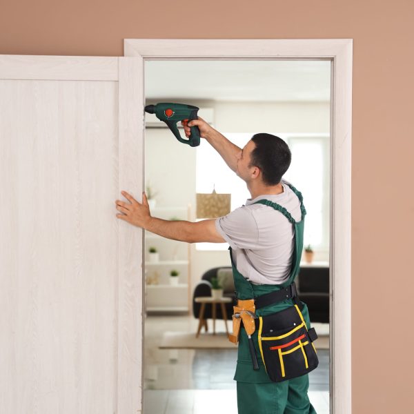 Male,Worker,With,Electric,Drill,Repairing,Door,At,Home